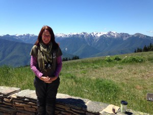Laurie Enright stands in front of  a stunning view of the Olympic Mountains.